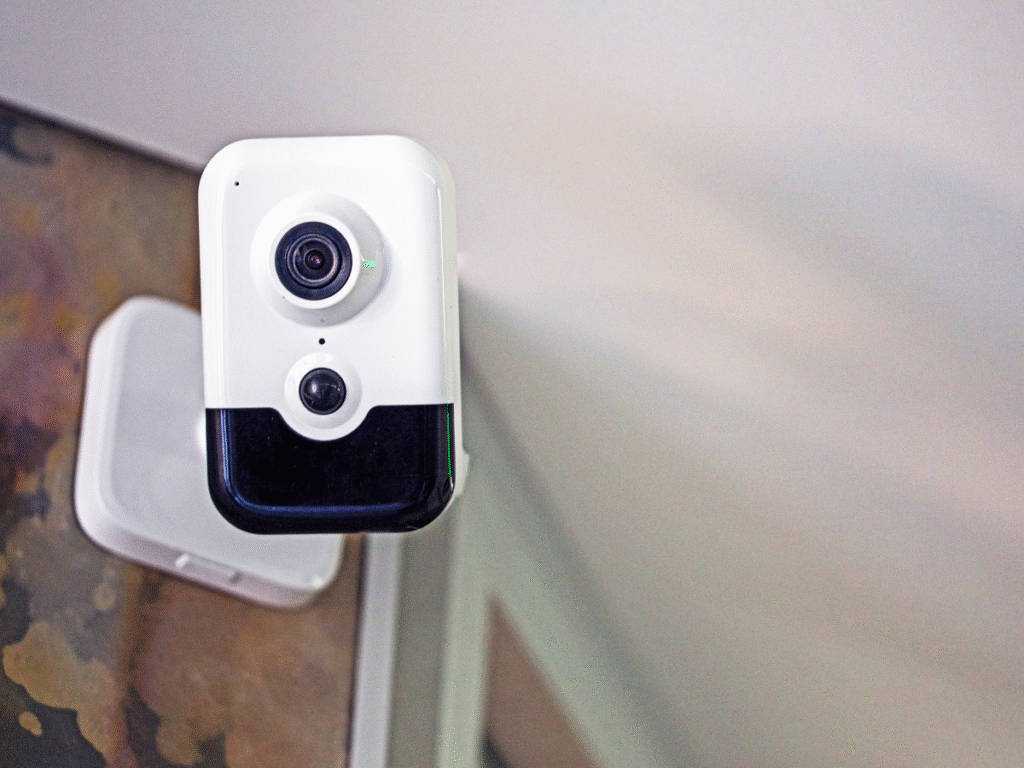 Indoor smart security camera installed near a doorway, showing motion sensor and wide-angle lens for home monitoring.